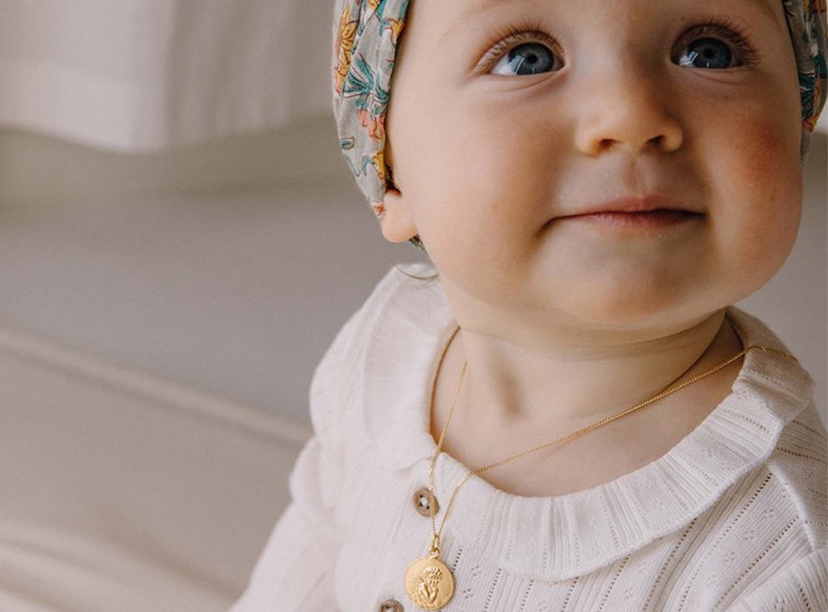 bébé avec médaille autour du cou